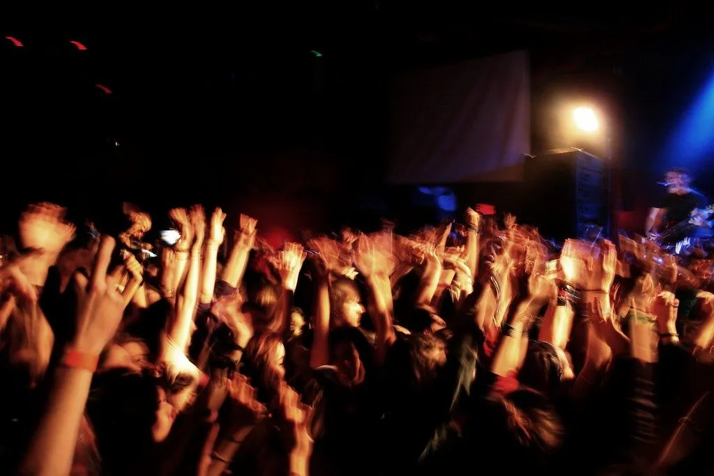 Foule en concert, mains levées dans la lumière des projecteurs