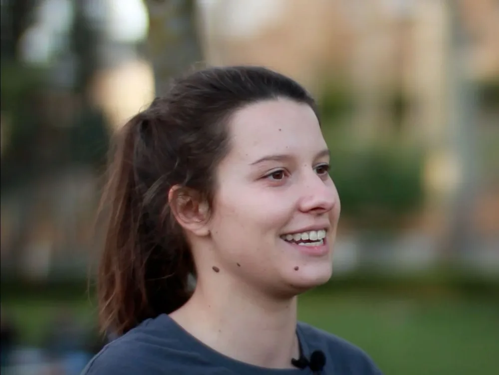 Visage d'une intervenante en interview, éclairé en lumière dorée, micro-cravate discret